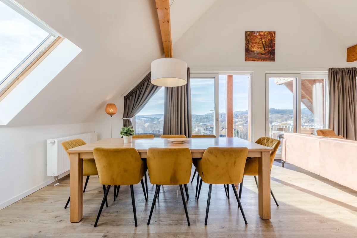 Langer Esstisch unter Dachschrägen mit Blick über den Ort
