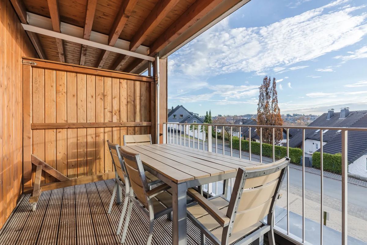 Holzbalkon mit Tisch und Blick auf den Ort