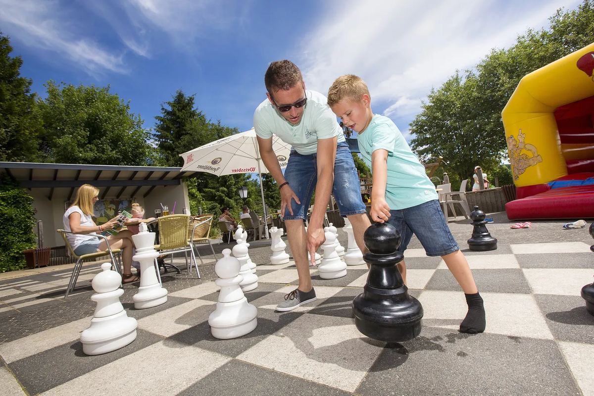 Vater und Sohn spielen mit großen Schachfiguren