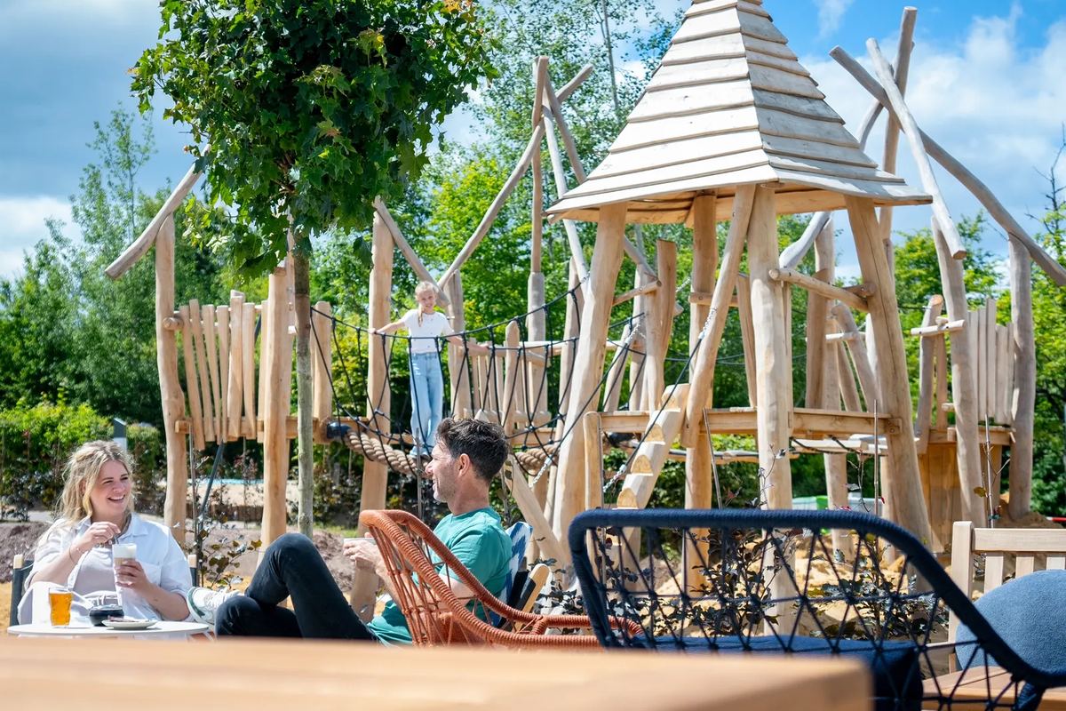 Holzspielplatz mit Türmen, daneben Sitzplätze