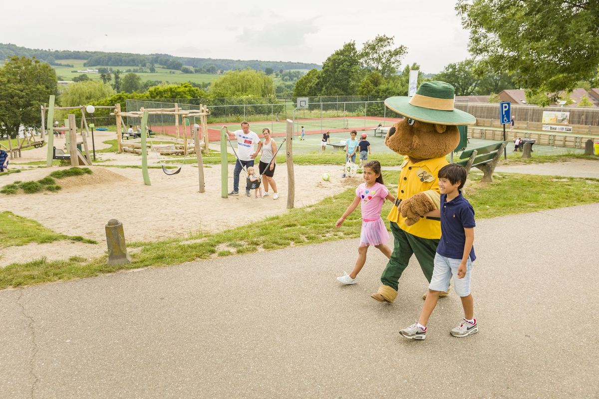 Kinder auf einem großen Spielplatz mit Maskottchen