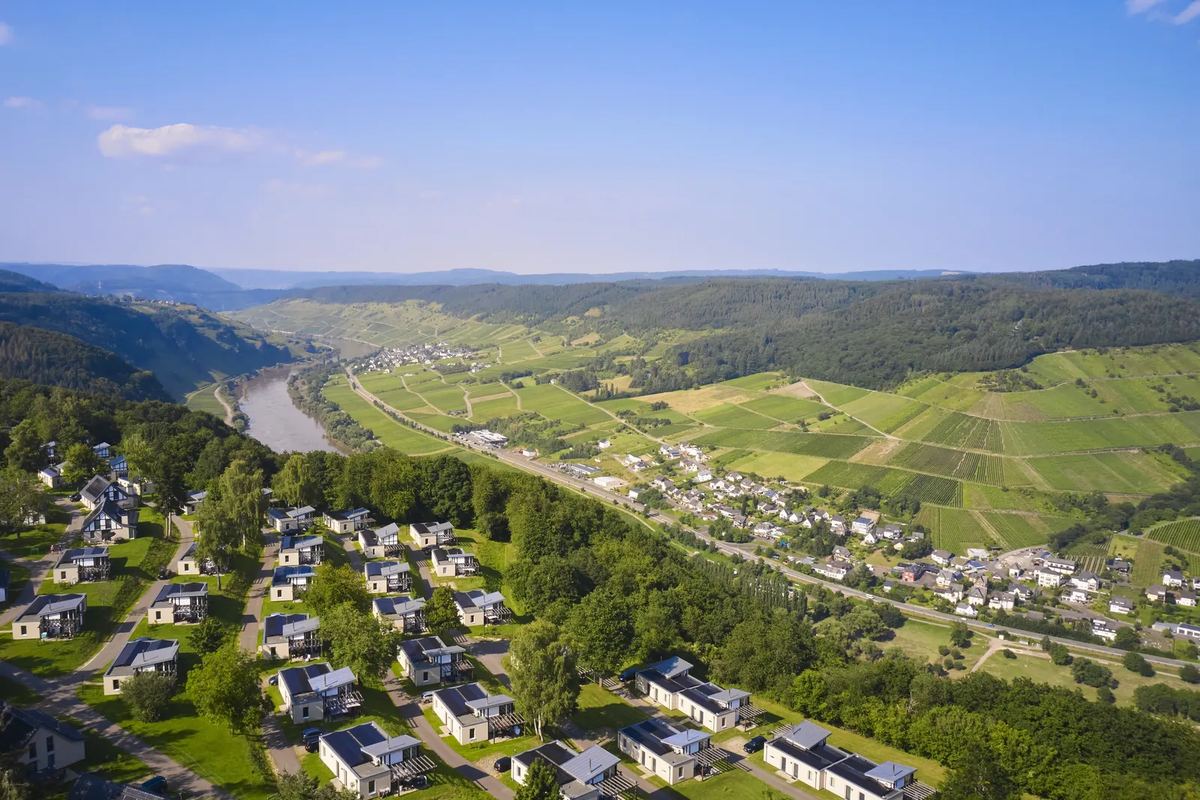 Luftbild: Ferienhäuser auf einer Anhöhe, darunter das Moseltal mit Weinbergen