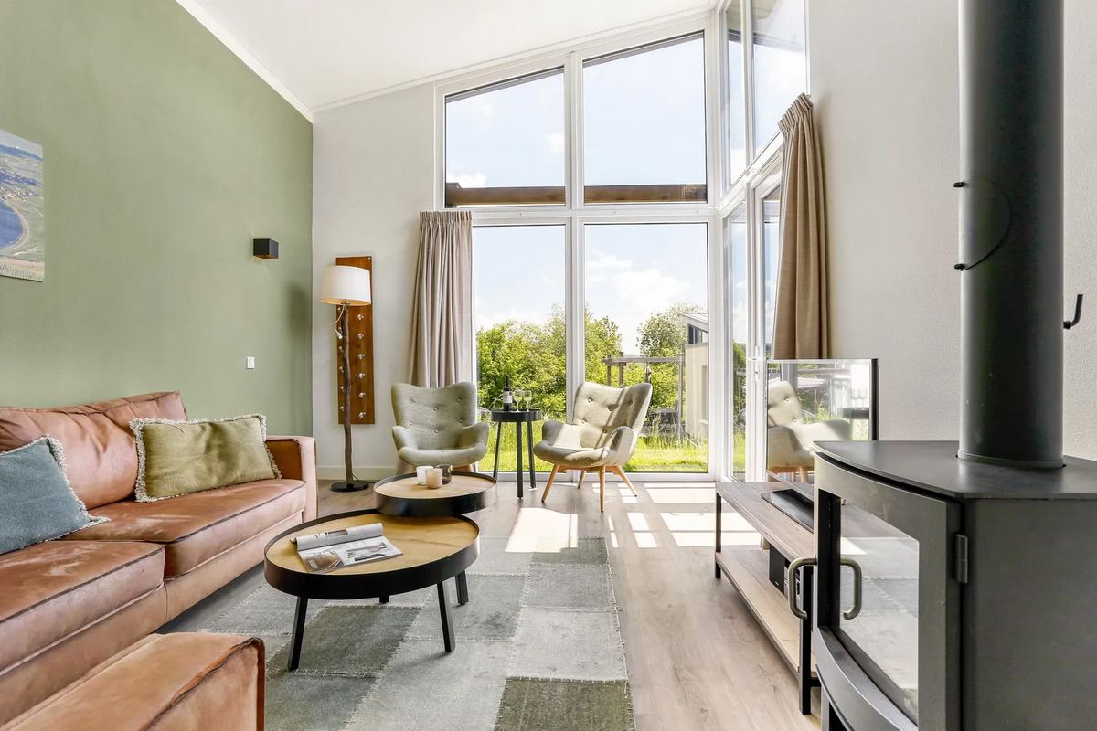 Wohnzimmer mit Ledersofa und Holzofen unter hoher Decke