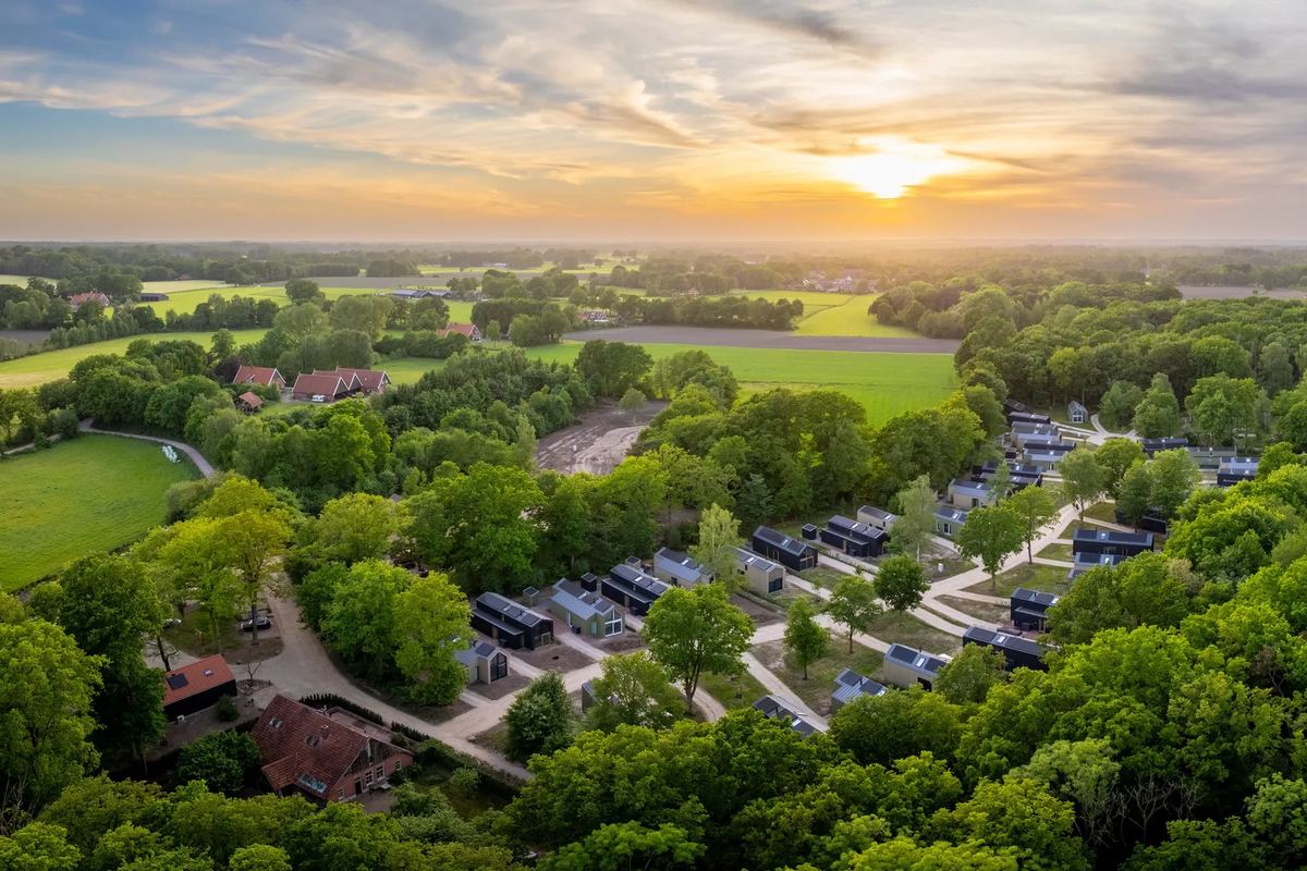 Luftbild: Ferienhäuser zwischen Bäumen und Feldern bei Sonnenuntergang