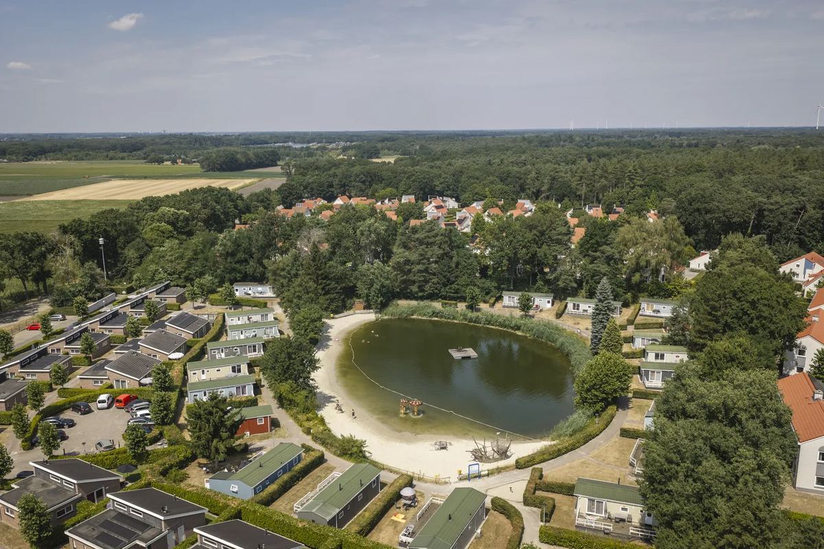 Luftbild: Ferienhäuser rund um einen Badesee mit Sandstrand