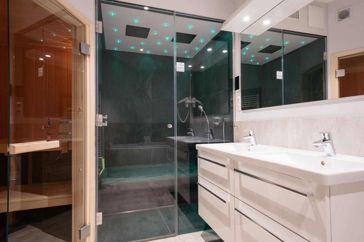 Badezimmer mit Saunakabine, Dusche und Doppelwaschbecken