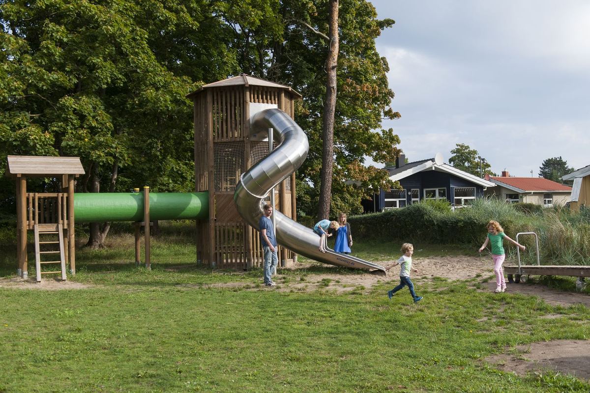 Spielplatz mit Turm und Rutsche zwischen Bäumen