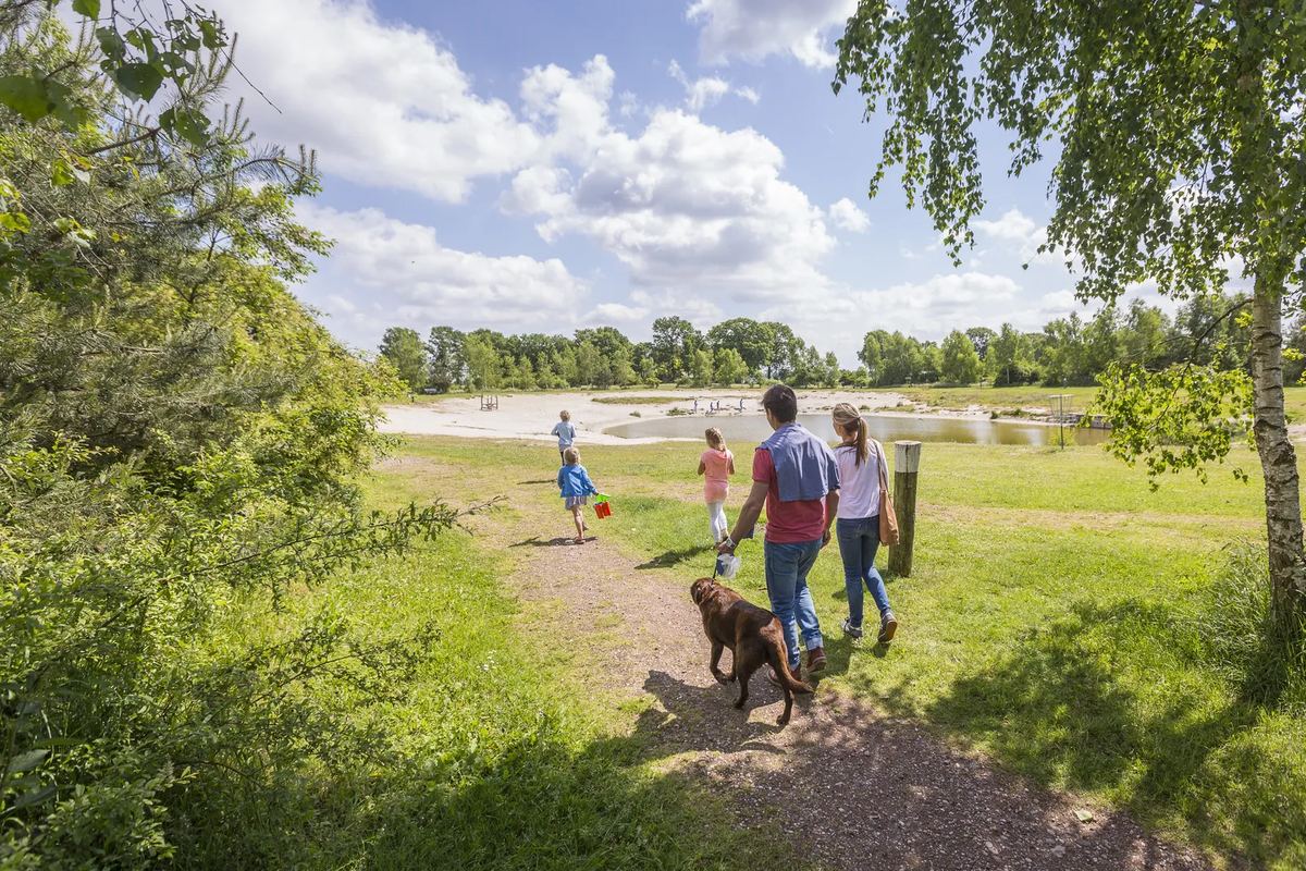 Familie mit Hund auf einem Weg an einem See