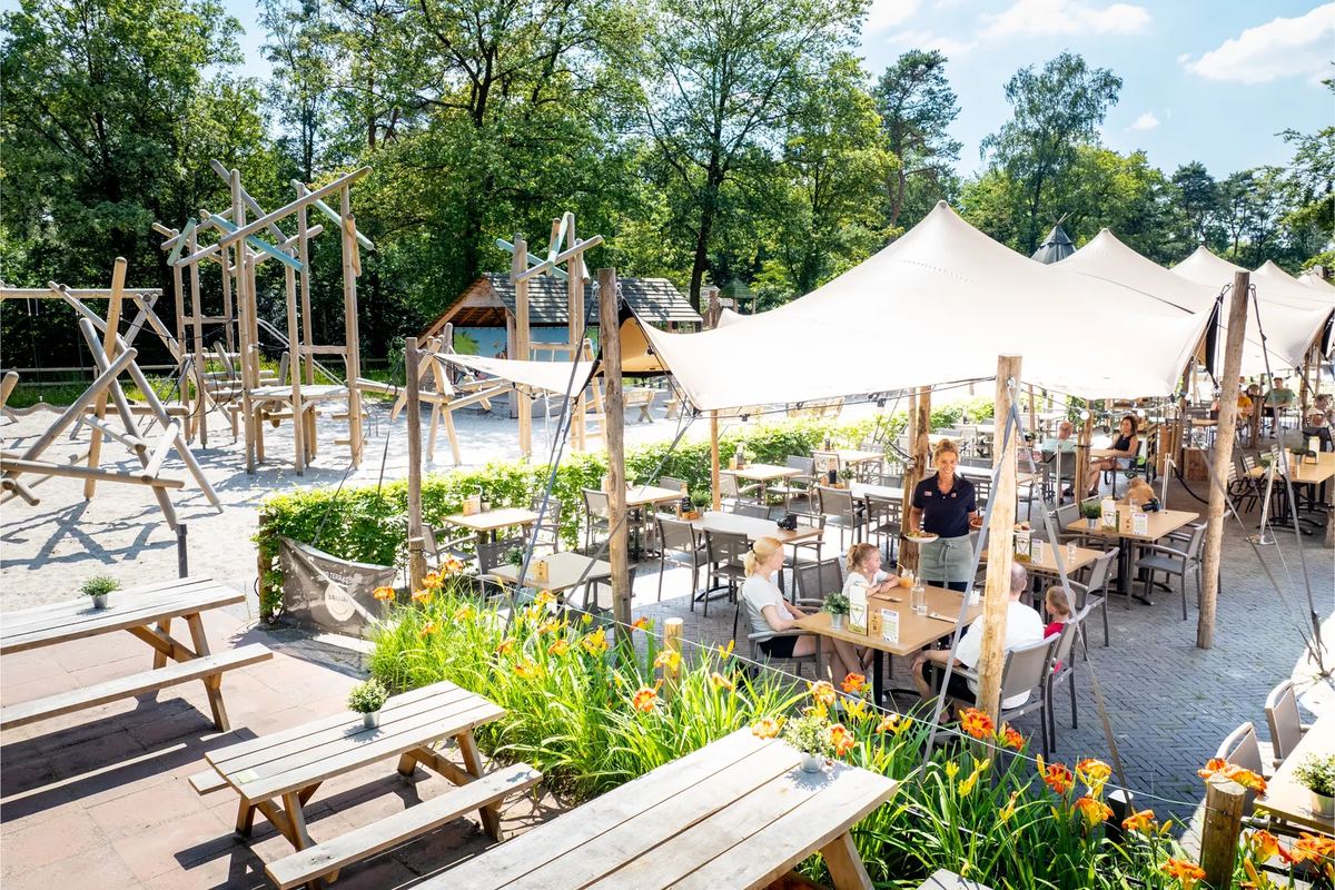 Terrasse mit Holztischen unter Sonnensegeln