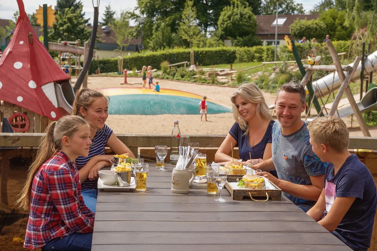 Familie isst mit Blick auf den Spielplatz