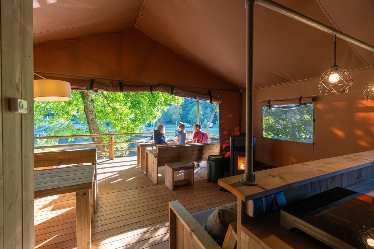 Überdachte Holzterrasse einer Zeltlodge mit Blick ins Grüne