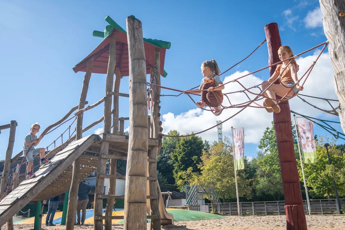 Kinder klettern auf einem Holzturm mit Netzen